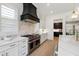 The kitchen has stainless steel oven with a black vent hood and white cabinets with brass pulls at 2805 Van Dyke Ave, Raleigh, NC 27607