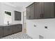 Bright laundry room with gray cabinets, black countertops, patterned tile flooring, and laundry closet at 2805 Van Dyke Ave, Raleigh, NC 27607