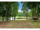 Scenic backyard featuring a tranquil pond framed by mature trees and a hammock stand at 3095 Champs Way, Mebane, NC 27302