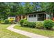 View of home showing gray siding, wood accents, and a stone walkway through manicured landscaping at 3095 Champs Way, Mebane, NC 27302