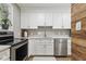 Modern kitchen featuring white cabinets, grey backsplash, stainless appliances, and quartz countertop at 4645 Edwards Mill Rd, Raleigh, NC 27612