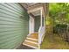 Side entrance featuring a wooden porch and stairs, leading to a white door and fenced yard at 507 N Elm St, Durham, NC 27701