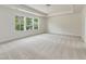 Bright, carpeted bedroom with a tray ceiling and three windows offering scenic views at 516 Winding Creek Dr, Lillington, NC 27546