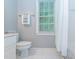 Bright bathroom with white tile flooring and toilet next to a window at 5401 Fire Pink Way, Raleigh, NC 27613