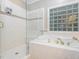 Bright bathroom features a soaking tub with gold fixtures, glass shower and glass block window at 5401 Fire Pink Way, Raleigh, NC 27613
