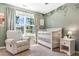 Bright Bedroom featuring a cozy recliner, white crib, leafy wall decor and large windows at 6 Beaver Creek Lane Ln, Durham, NC 27703
