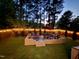 This backyard offers an inviting patio with a firepit and fence strung with decorative lights for nighttime enjoyment at 647 N Hardee St, Durham, NC 27703