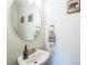 Simple powder room featuring a pedestal sink, round mirror, and modern wall decor at 647 N Hardee St, Durham, NC 27703