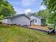Back exterior view shows an expansive backyard, landscaped with bushes and trees at 707 Lakewood Dr, Siler City, NC 27344