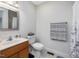 Well-lit bathroom with neutral tile, wood vanity, and a shower with curtain at 707 Lakewood Dr, Siler City, NC 27344