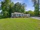 The house with light-blue siding is surrounded by lush greenery and mature trees at 707 Lakewood Dr, Siler City, NC 27344