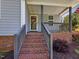 Close up of the brick steps and grey porch with a storm door with a wreath on it at 707 Lakewood Dr, Siler City, NC 27344