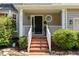 A welcoming front porch features white railings, brick steps, and decorative plants for curb appeal at 8512 Erinsbrook Dr, Raleigh, NC 27617