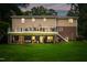 Evening view of the backyard featuring a deck with patio lights, ideal for evening relaxation and outdoor gatherings at 8608 Valley Brook Dr, Raleigh, NC 27613