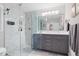 Modern bathroom featuring a glass shower, double vanity with gray cabinets, and marble-tiled walls at 8608 Valley Brook Dr, Raleigh, NC 27613