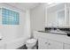 Bright bathroom features a tub, modern vanity with granite countertop, and unique glass block window at 8608 Valley Brook Dr, Raleigh, NC 27613