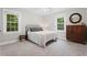 Bright bedroom with neutral tones, two windows, light carpet and a wooden dresser with round mirror at 8608 Valley Brook Dr, Raleigh, NC 27613