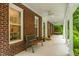 Inviting front porch featuring a cozy bench, ceiling fans, and classic brick columns at 8608 Valley Brook Dr, Raleigh, NC 27613