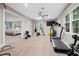 Home gym featuring workout equipment, ceiling fan, wood-look flooring and an open view of the bedroom at 8608 Valley Brook Dr, Raleigh, NC 27613