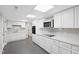 Modern basement kitchen with stainless appliances, white cabinetry, and gray tile flooring at 8608 Valley Brook Dr, Raleigh, NC 27613