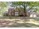 Large, brick two-story home in a yard with mature trees and a fire pit at 938 Hargrove St, Henderson, NC 27536