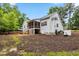 Spacious backyard featuring a brick patio, stairs leading up to a screened porch, lush trees, and grass at 100 Lexington Ave, Zebulon, NC 27597