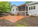 View of backyard featuring a brick patio, stairs leading up to a screened porch, and lush trees at 100 Lexington Ave, Zebulon, NC 27597