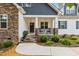Close-up of the cozy front porch featuring rocking chairs, stone pillars, and a landscaped garden at 100 Lexington Ave, Zebulon, NC 27597