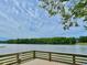Scenic lake view with wooden deck and tree line in the background under a partly cloudy sky at 104 Odessa Cir, Cary, NC 27513