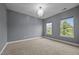 Neutral bedroom with a chandelier and natural light from two windows overlooking greenery at 1144 Survada Ln, Morrisville, NC 27560