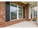 Detailed view of a brick-accented porch featuring black shutters and an inviting front door at 1144 Survada Ln, Morrisville, NC 27560