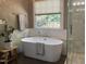 Modern bathroom featuring a freestanding soaking tub, a window, and a glass-enclosed shower at 121 Flint Point Ln, Holly Springs, NC 27540