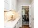 Convenient butler's pantry with white cabinets, stylish backsplash, and quartz countertops, enhancing functionality at 121 Flint Point Ln, Holly Springs, NC 27540