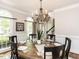 Elegant dining room featuring a chandelier, large windows, and a table set for six, ideal for gatherings at 121 Flint Point Ln, Holly Springs, NC 27540