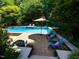 Inviting in-ground pool with a patio, waterfall feature and an umbrella for shade surrounded by mature trees and landscaping at 121 Flint Point Ln, Holly Springs, NC 27540