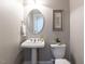 Stylish powder room with a pedestal sink, oval mirror, and neutral wall color at 121 Flint Point Ln, Holly Springs, NC 27540
