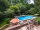 Aerial view of a refreshing swimming pool and spa surrounded by mature landscaping and a deck at 121 Flint Point Ln, Holly Springs, NC 27540