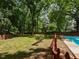 Spacious backyard with well-maintained lawn, mature trees, pool, and wooden fence at 1215 Brookgreen Dr, Cary, NC 27511