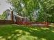 Grassy backyard with pool, red deck, wooden privacy fence, and mature trees at 1215 Brookgreen Dr, Cary, NC 27511