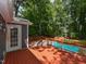 Backyard pool with a red deck, wooden fence, and lush green trees at 1215 Brookgreen Dr, Cary, NC 27511