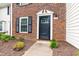 Close-up of brick townhome entrance with black door, white trim, and landscaped walkway at 129 Assembly Ct, Cary, NC 27511