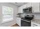 Bright, modern kitchen with white cabinets, stainless appliances, and light countertops at 129 Assembly Ct, Cary, NC 27511