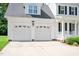 Two-car garage with decorative windows on a home with white trim and black shutters at 1605 Baneberry Ct, Willow Springs, NC 27592