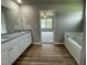 Open-concept bathroom with double granite vanity, soaking tub, wood-look flooring, and view to the bedroom at 186 Coharie Dr, Lillington, NC 27546