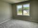 Neutral bedroom features plush carpet, gray walls, and a bright window overlooking the green landscape at 186 Coharie Dr, Lillington, NC 27546