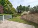 Grassy backyard showcasing a retaining wall, white fence, and lush greenery at 207 Callum Pl, Cary, NC 27519
