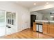 Bright kitchen featuring stainless steel appliances, access to the sunroom, and hardwood floors at 207 Callum Pl, Cary, NC 27519