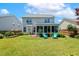 Manicured backyard featuring lush green grass, mature landscaping, and comfortable outdoor seating area at 2128 Feather Ridge Dr, Holly Springs, NC 27540