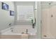 Bright bathroom featuring a soaking tub beneath a window and a glass-enclosed shower at 2128 Feather Ridge Dr, Holly Springs, NC 27540