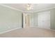 Neutral-toned bedroom with large closet, ceiling fan, and open doorway to the hall at 2128 Feather Ridge Dr, Holly Springs, NC 27540